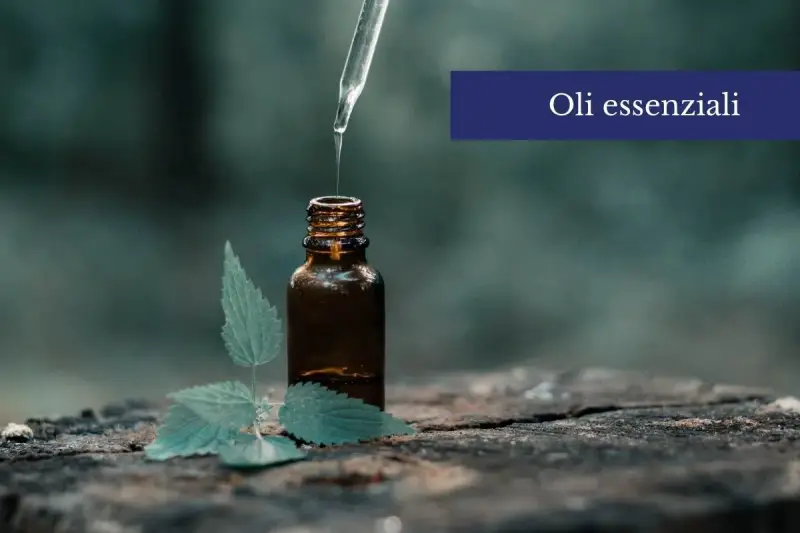 Una goccia di olio essenziale cade da un contagocce in una bottiglia ambrata, accanto a una foglia verde. Scopri come usare gli oli essenziali sulla pelle per un benessere naturale.
