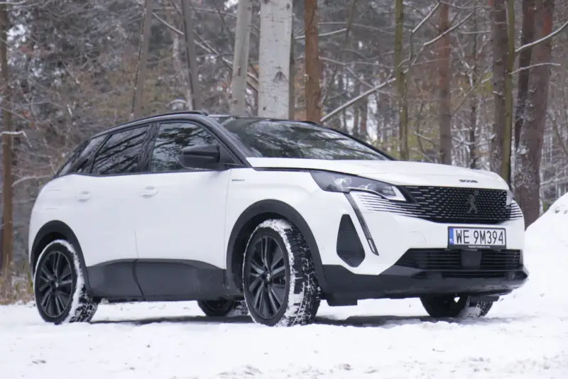 Biały Peugeot 3008 hybryda na śniegu, gotowy na zimowe przygody w lesie.