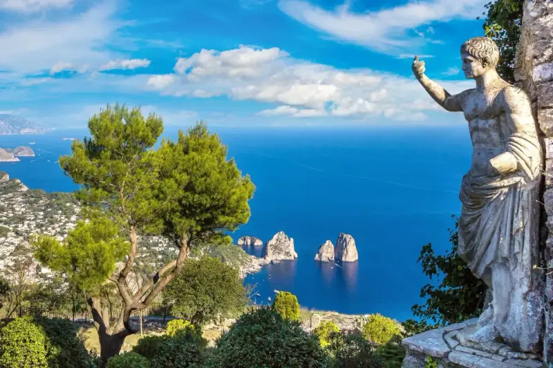 Statua antica guarda il mare blu intenso e i Faraglioni, icona dell'isola vicino Capri.