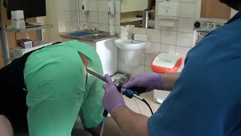 Lekarz w rękawiczkach wykonuje badanie jelit za pomocą endoskopu.