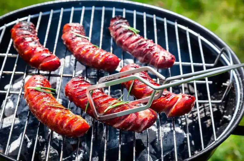 Aromatyczna kiełbasa z grilla, skwiercząca na węglu, z gałązkami rozmarynu. Idealna na letnie popołudnie.