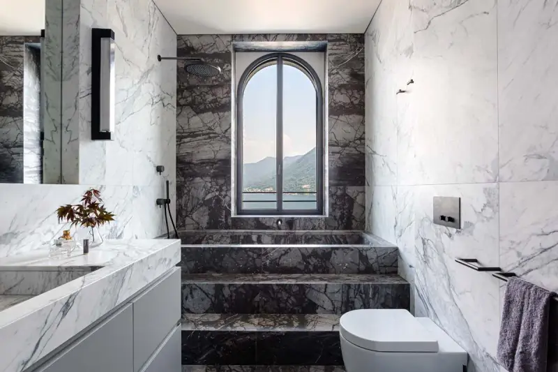 Bagno di lusso con vasca doccia in muratura, rivestimenti in marmo e vista panoramica.
