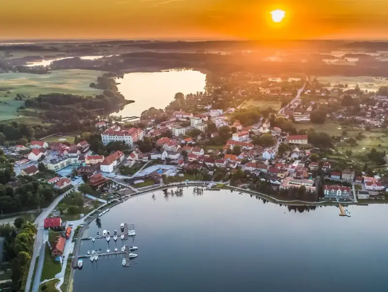 Malownicze miasteczko nad jeziorem o zachodzie słońca. Idealne miejsce na wykorzystanie bonu turystycznego i odpoczynek.