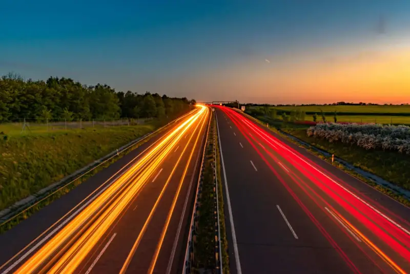 Ljusspår av bilar på en tysk autobahn vid solnedgången.