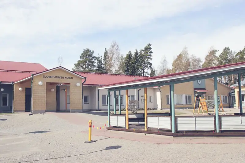 Suomusjärven Koulu, czyli szkoła w Finlandii, z placem zabaw i zielonymi terenami. Ciekawostki o fińskim systemie edukacji często podkreślają jego innowacyjność.