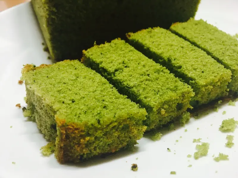 Puszyste ciasto matcha pokrojone w prostokątne kawałki, ułożone na białym talerzu.