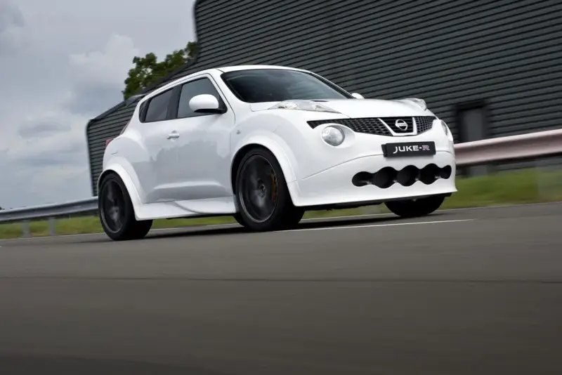 Biały Nissan Juke-R pędzi po torze, jego sportowy wygląd podkreślają szerokie nadkola i agresywny przedni zderzak.