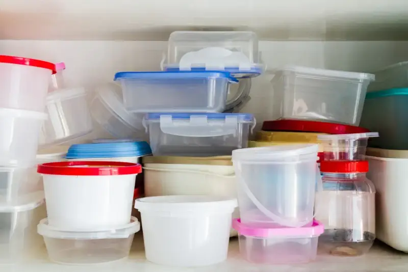 Stos pojemników na żywność, niektóre z kolorowymi pokrywkami. Uważaj na ftalany w plastiku.