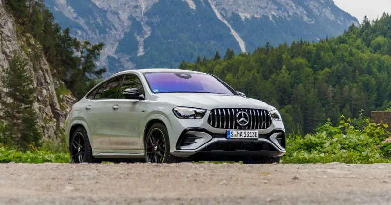 Biały Mercedes GLE 53 AMG coupe na tle górskiego krajobrazu z lasem.