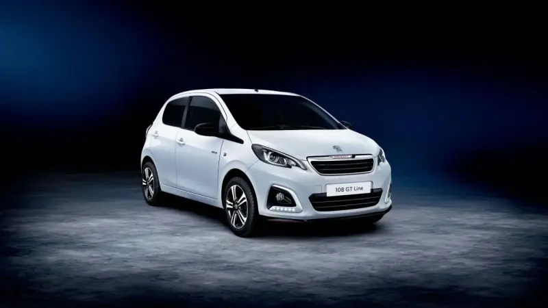 Biały Peugeot 108 GT Line stoi na ciemnym tle.