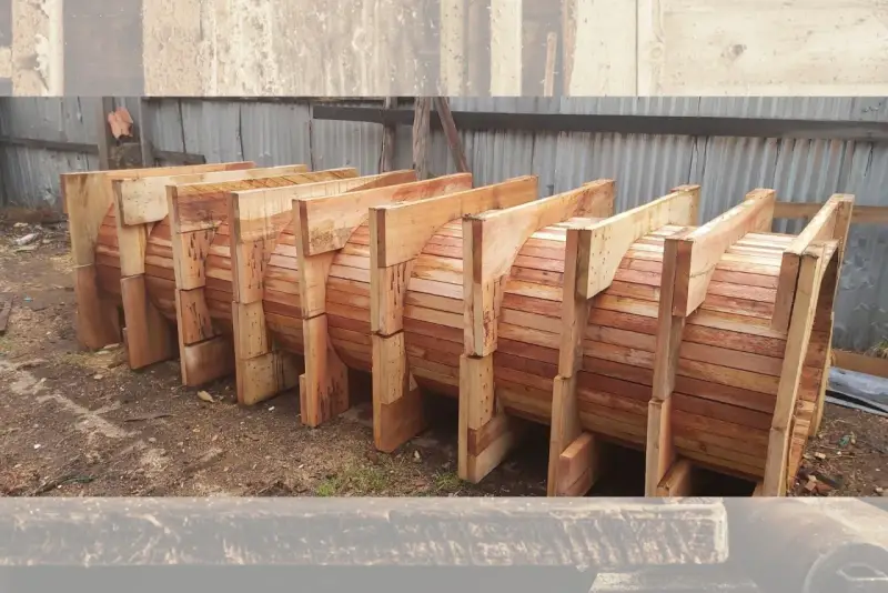 Encofrados de madera apilados, listos para dar forma a grandes estructuras circulares.