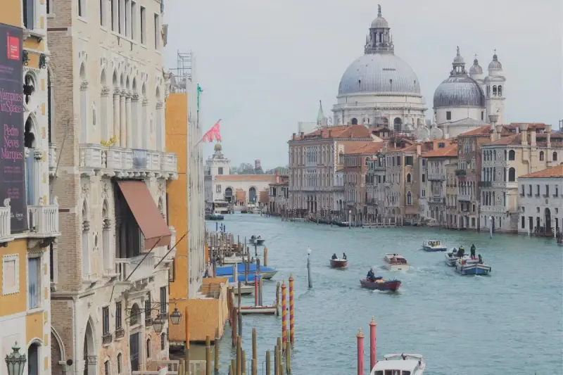 Canali di Venezia, con barche e palazzi storici. Un assaggio di cosa vedere a Venezia in un giorno, tra cupole imponenti e acque azzurre.