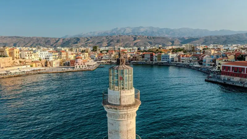 Latarnia morska wenecka w Chanii, prom na Krecie, z widokiem na port i góry w tle.