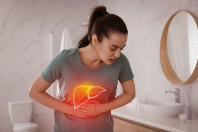 Kobieta trzyma się za brzuch, gdzie widoczna jest podświetlona wątroba. Czy to objaw choroby?