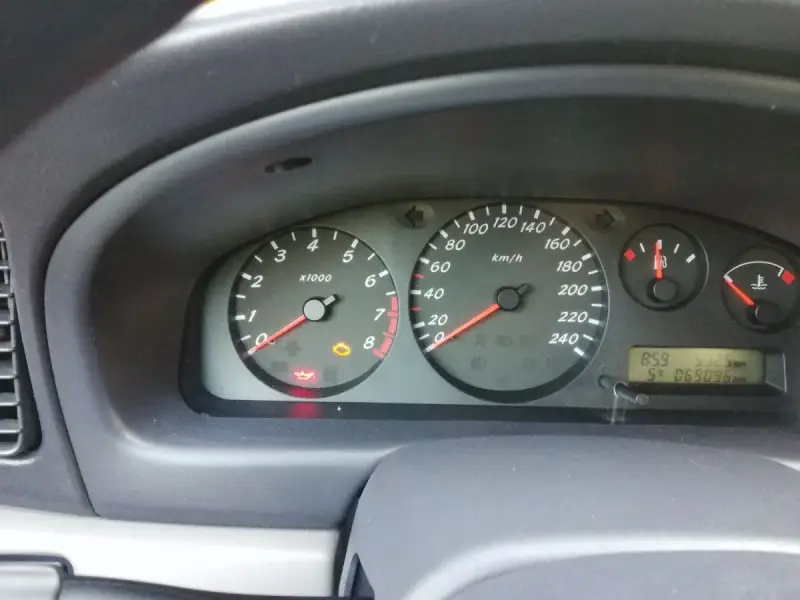 Migająca kontrolka samochodu z kluczykiem Nissan na desce rozdzielczej. Obok świeci się kontrolka oleju.