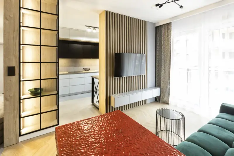 Nowoczesny, bardzo mały salon w bloku z otwartą kuchnią, drewnianymi panelami i designerskimi meblami.