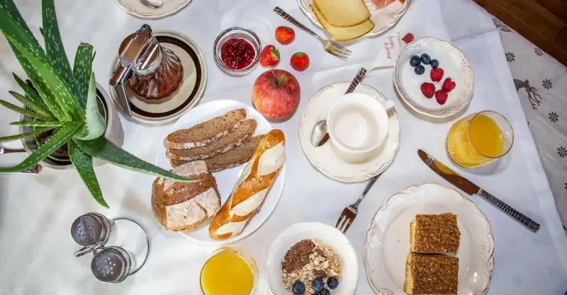 Un ricco e genuino **colazione contadina** con pane integrale, marmellata, frutta fresca, yogurt, succo d'arancia e dolcetti.