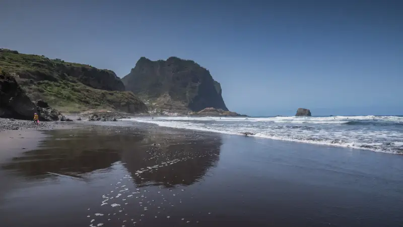Dziecko bawi się na czarnej plaży Madera, w tle widać skaliste klify i ocean.