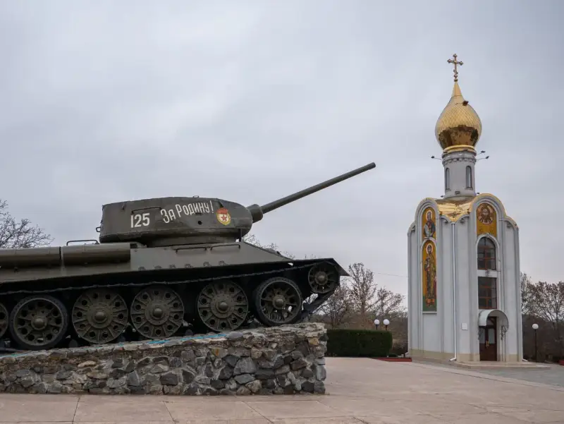 Czołg z napisem "Za Rodinu!" stoi obok cerkwi z złotą kopułą. Pomnik na nadniestrze.