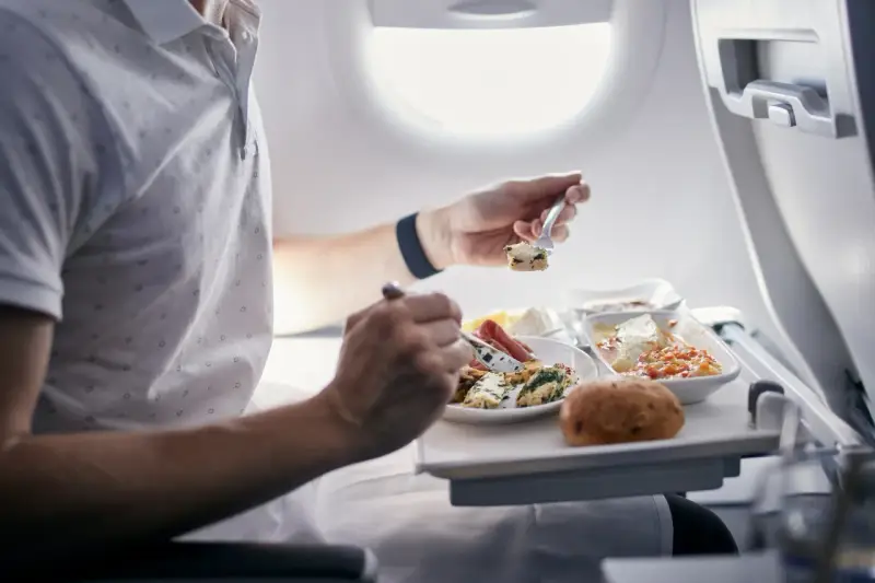Pasażer je posiłek na pokładzie samolotu. Zastanawiasz się, czy można przewozić jedzenie w bagażu rejestrowanym Ryanair?