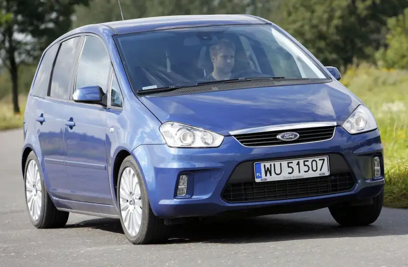Niebieski Ford C-Max 1.6 TDCI z mężczyzną za kierownicą jedzie po drodze wśród zieleni.