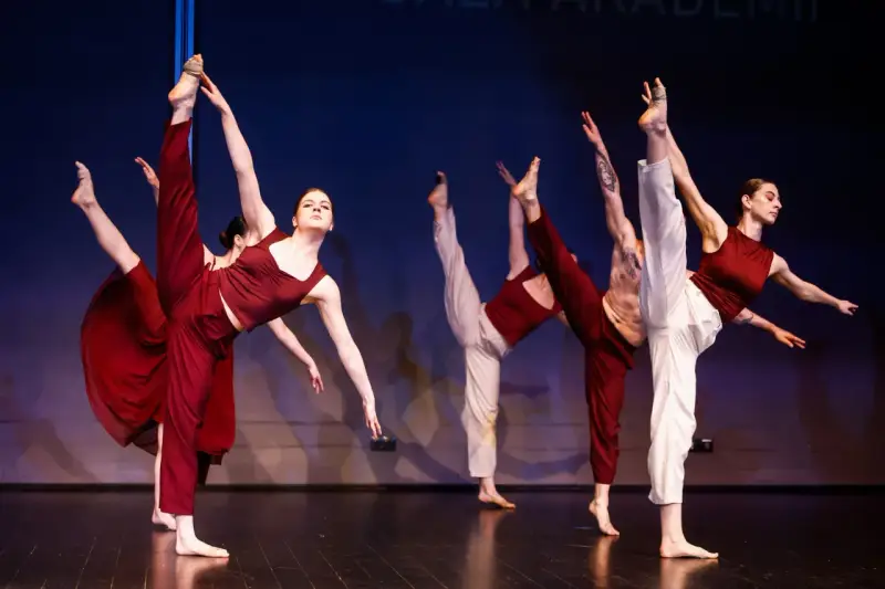Tancerze wykonują dynamiczny jazz dance, unosząc nogi w powietrze.