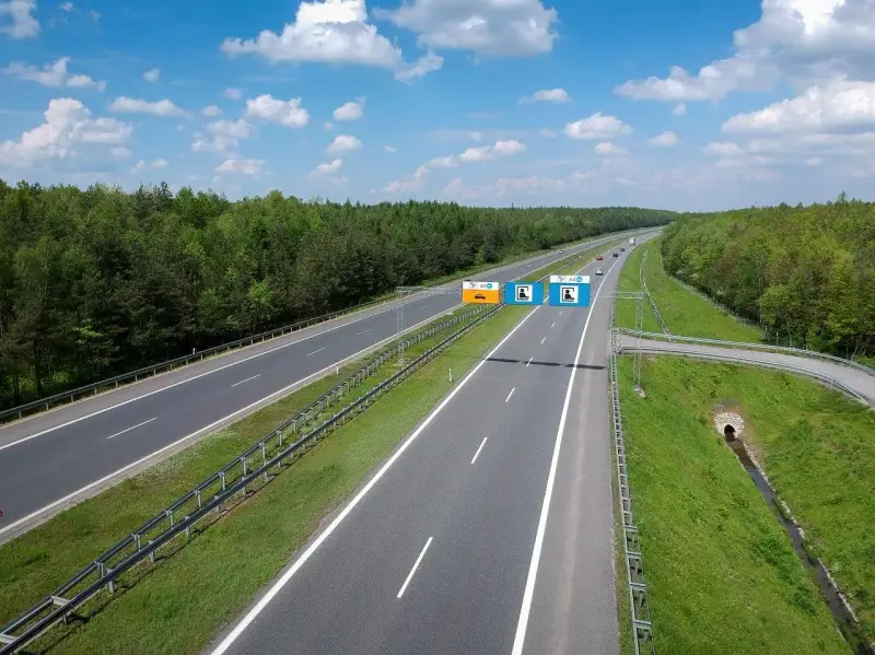 Znaki na autostradzie A4 informują, czy jest ona płatna. Widok na pustą autostradę w słoneczny dzień.