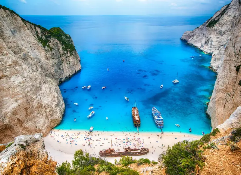 Zatoka Navagio, najcieplejsza wyspa grecka, z turkusową wodą, białym piaskiem, statkami i wrakiem.