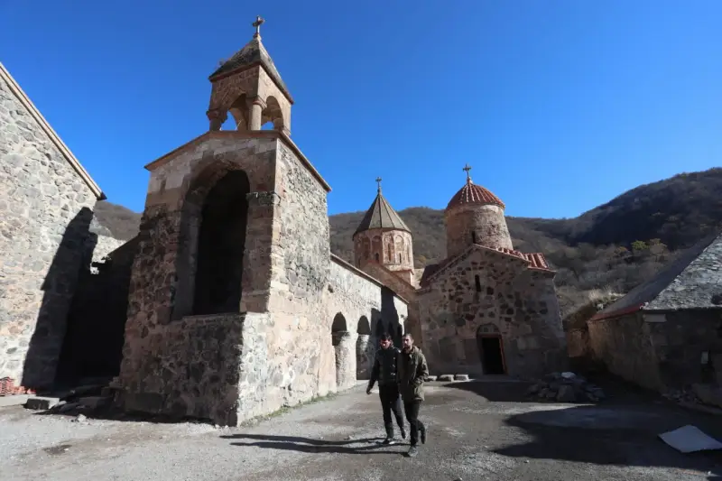Kamienny klasztor w Armenii, świadectwo bogatej historii i religii. Dwóch mężczyzn spaceruje po dziedzińcu.