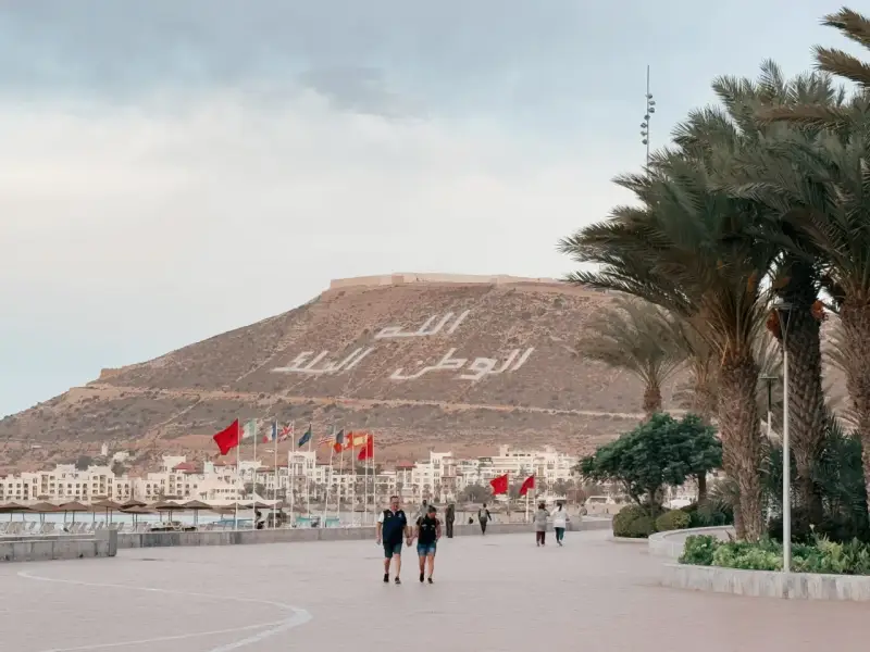 Spacerem po promenadzie w Agadirze, z widokiem na miasto i napisem na wzgórzu. Czy Agadir jest bezpieczny? Tak, wygląda na spokojne miejsce.