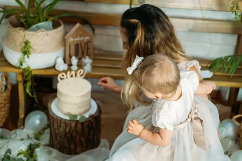 Mama z córką przy torcie na roczek. Piękny tort i dekoracje, idealne na prezent, co kladzie sie dziecku do wyboru na roczek.