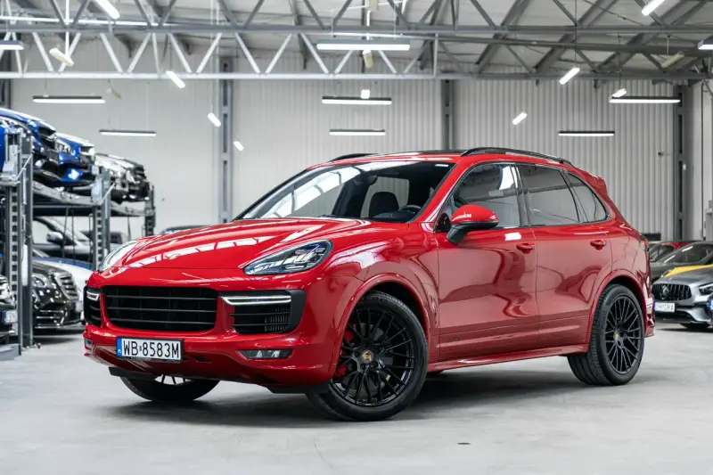 Czerwony Porsche Cayenne GTS lśni w salonie, gotowy na podbój dróg.