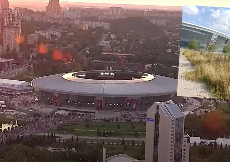 Donbass Arena w blasku zachodzącego słońca, otoczona miejskim krajobrazem i tłumami ludzi.