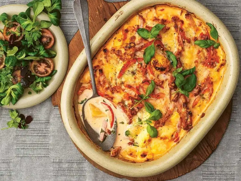 En krämig kasslergratäng med ost och örter, serverad med en fräsch sallad. Ett perfekt kassler recept för middagen.