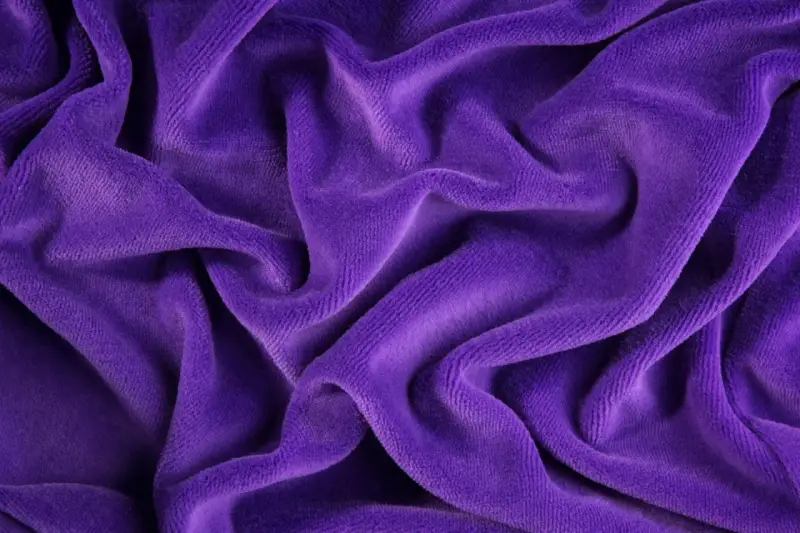 Tessuto di velluto viola drappeggiato, morbido e soffice. Scopri come lavare il velluto per mantenerlo splendente.