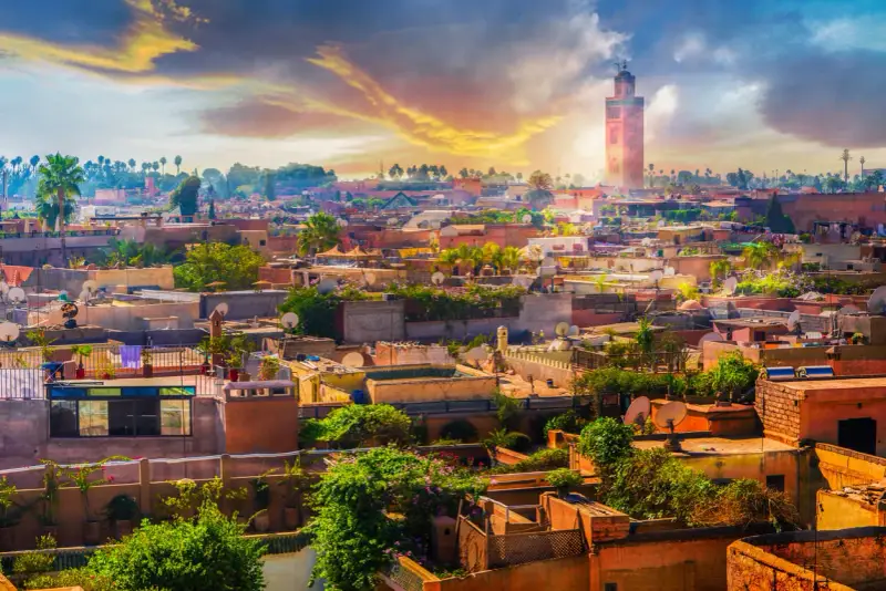 Marrakesz w styczniu: słoneczna pogoda nad miastem z minaretem Koutoubia w tle. Dachy pełne zieleni i anten satelitarnych.