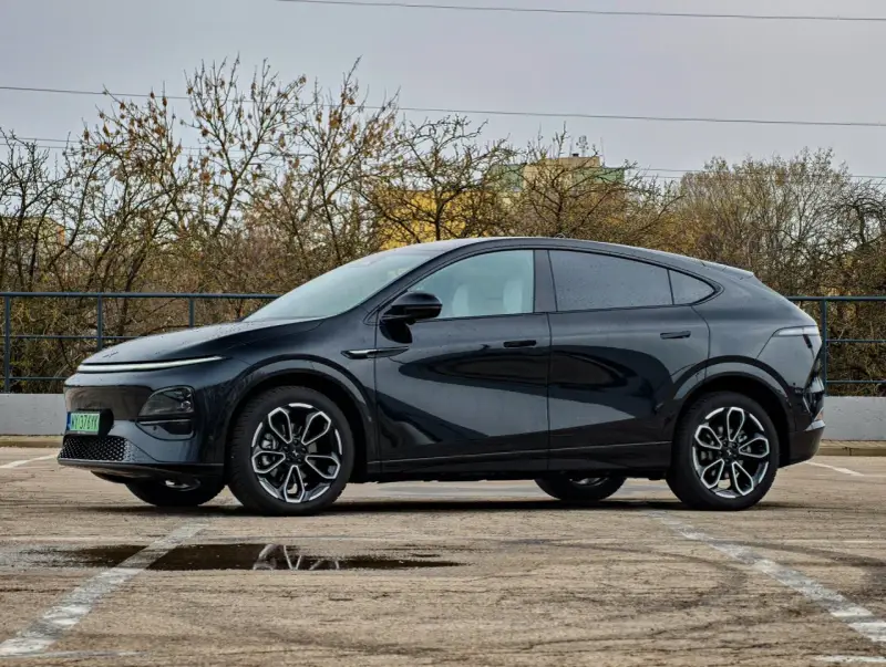 Elegancki, czarny Xpeng G6 stoi na parkingu, odbijając się w kałużach.