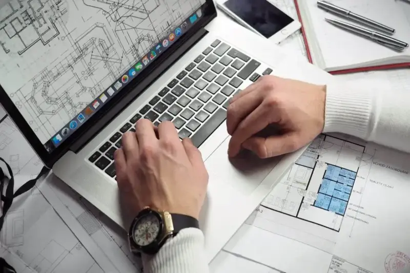 Architekt pracuje nad projektem na laptopie, analizując plany. Zastanawiasz się, ile zarabia architekt?