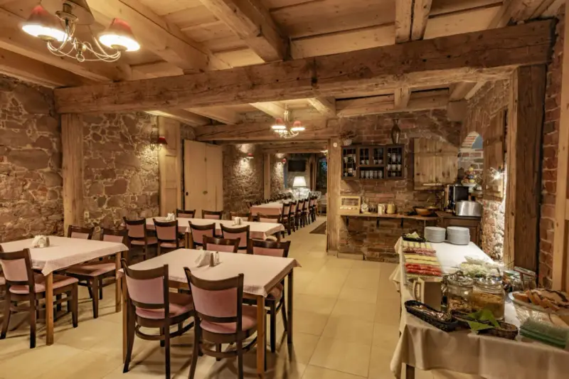 Przytulna restauracja w stylu rustykalnym, z kamiennymi ścianami i drewnianymi belkami. Idealne miejsce na posiłek w twierdzy Srebrna Góra.