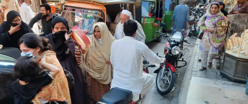 Ludzie na ulicy w Pakistanie, wśród nich kobiety w hidżabach i dzieci. Czy pakistan jest bezpieczny? Tłum na targu, ruchliwa ulica.