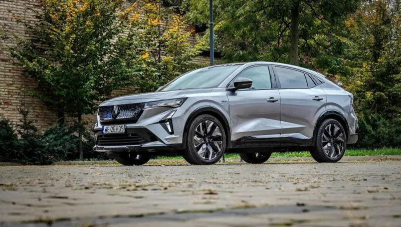 Nowy Renault Rafale, elegancki SUV coupe, prezentuje się na tle jesiennej zieleni i ceglanej ściany.