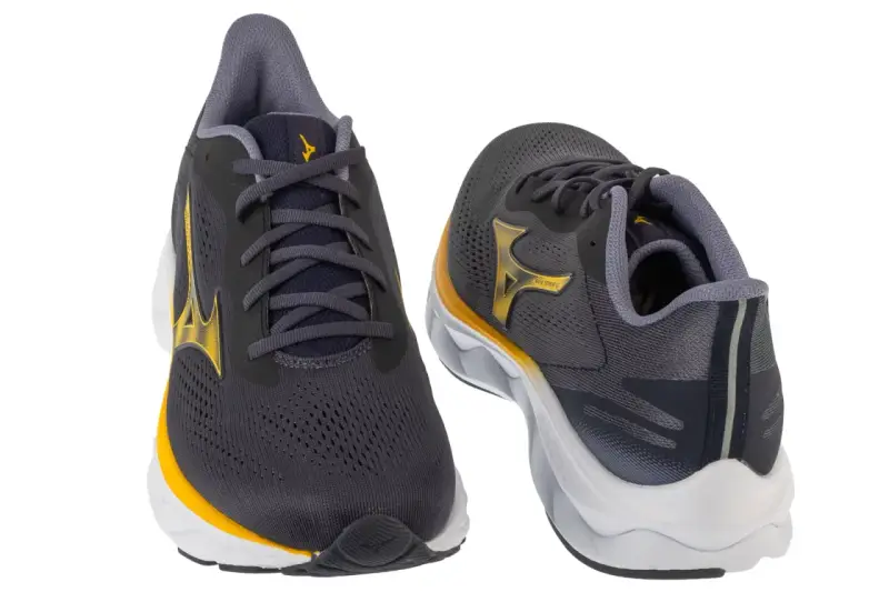 Dwa buty do biegania Mizuno w kolorze grafitowym z żółtymi akcentami. Mizuno to znana firma sportowa.
