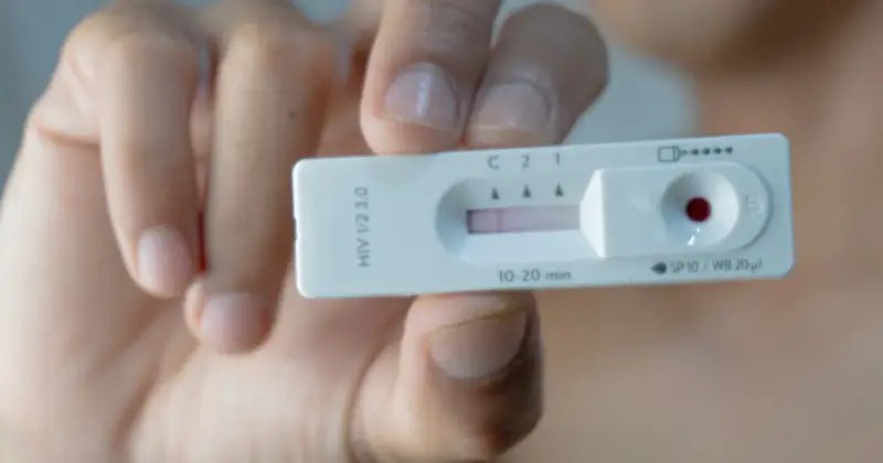Dłoń trzyma test na HIV z widocznym wynikiem.