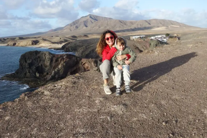 Mamma e bambino felici a Lanzarote con bambini, con vista sulle scogliere e montagne vulcaniche.