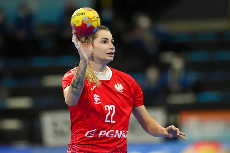 Aleksandra Rosiak w akcji, rzuca piłkę ręczną. Zawodniczka w czerwonej koszulce z numerem 22.