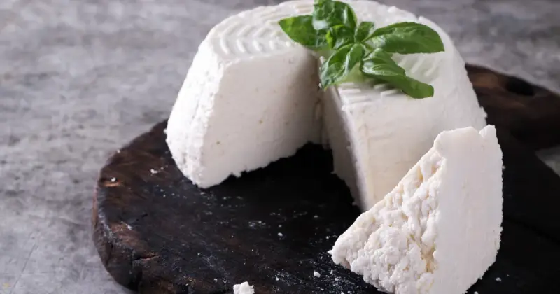 Świeża ricotta z bazylią na ciemnej desce. Idealna do lekkich posiłków, dbając o ricotta kcal.