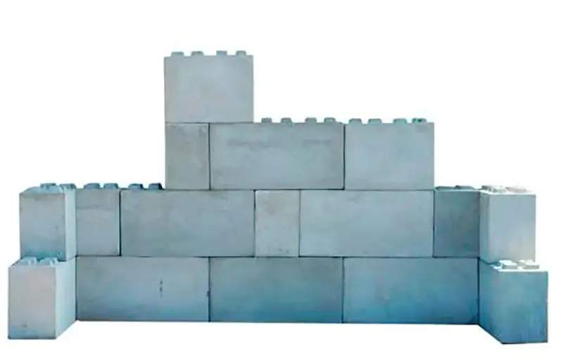 Una pared de bloques grises, apilados de forma irregular, simula un castillo de juguete.