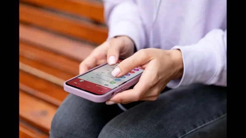 Dłonie kobiety obsługują smartfon, czując subtelne wibracje haptyczne przy każdym dotknięciu ekranu.