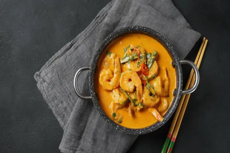 Aksamitne tajskie curry z krewetkami, podane w garnuszku z pałeczkami.