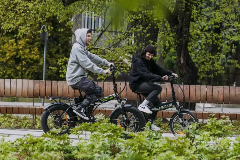 Dwaj młodzi ludzie cieszą się jazdą na rowerach elektrycznych. Dofinansowanie do roweru elektrycznego sprawia, że ekologiczny transport jest dostępny dla każdego.